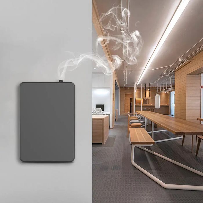 מפיץ ריח חשמלי על קיר בחלל מודרני, פולט עשן ריחני לאווירה נעימה.