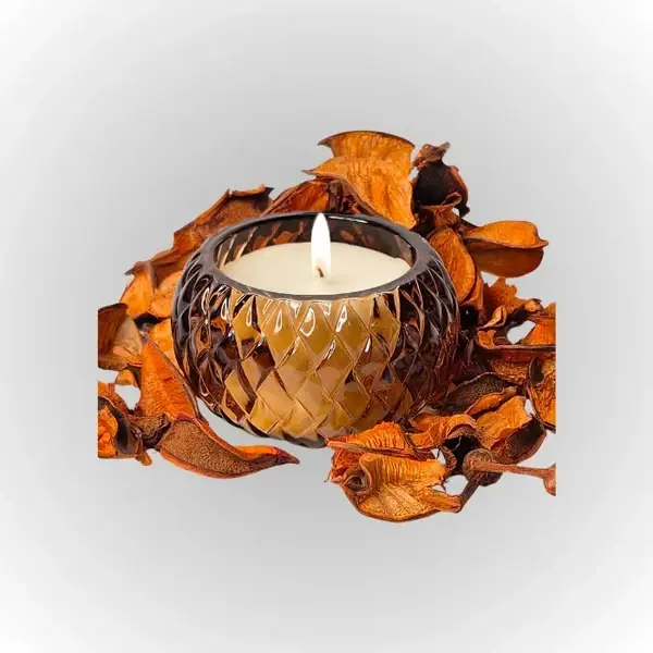 נר סויה ריחני בתוך כלי מעוצב, מוקף בקליפות צמחים מיובשות ליצירת אווירה נעימה.