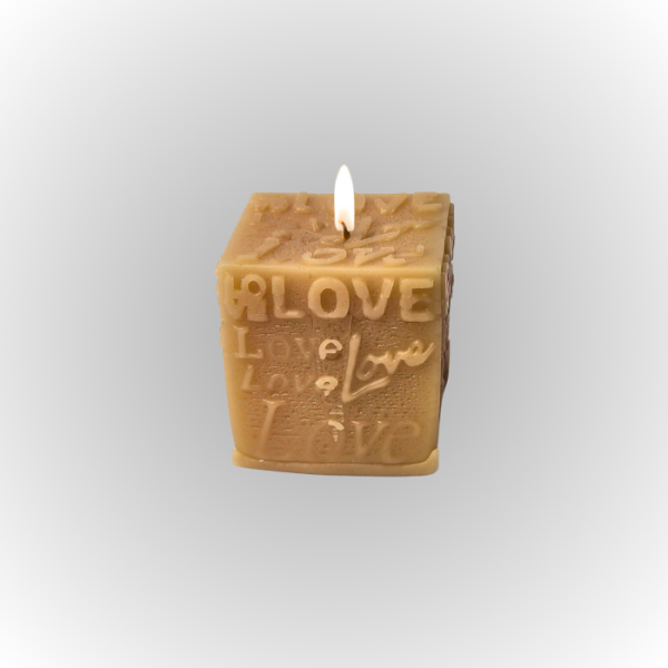 נר סויה ריחני בצורת קוביה עם הכיתוב "LOVE" בולט, מואר באור דולק.