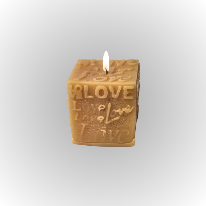 נר סויה ריחני בצורת קוביה עם הכיתוב "LOVE" בולט, מואר באור דולק.