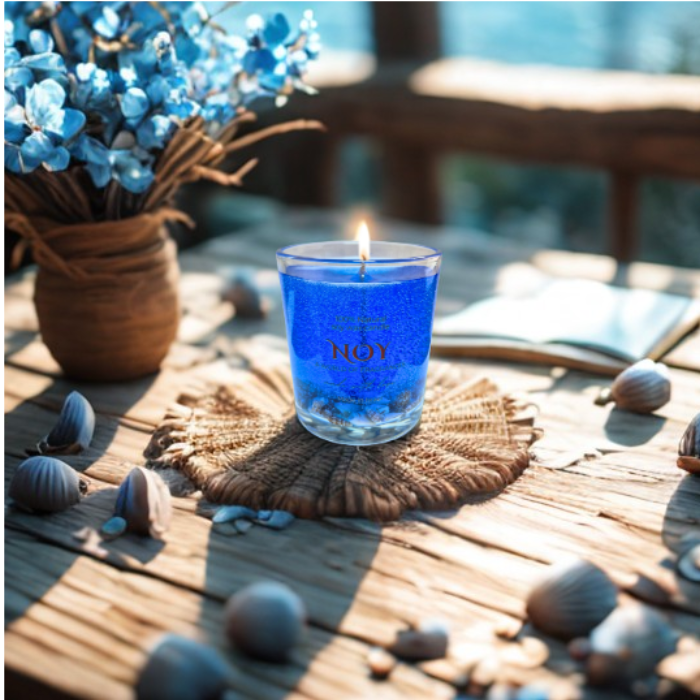 נר ג'ל מעוצב נר סויה ריחני בצבע כחול על שולחן עץ, מוקף בפרחים ובעלי חיים קטנים. אידיאלי לריח לבית.