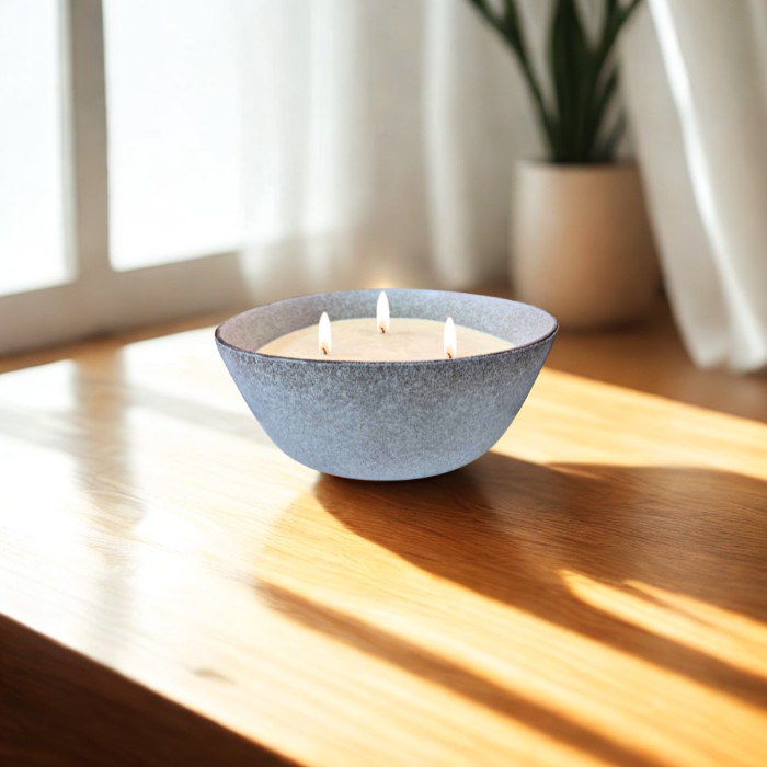 נר סויה Stone Bowl נר סויה ריחני עם שלושה פתילים מונח על שולחן עץ, מואר באור טבעי, משתלב בסביבה נינוחה.